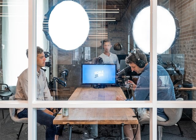 Journalist in a studio with bright lights sitting at the table and recording a podcast